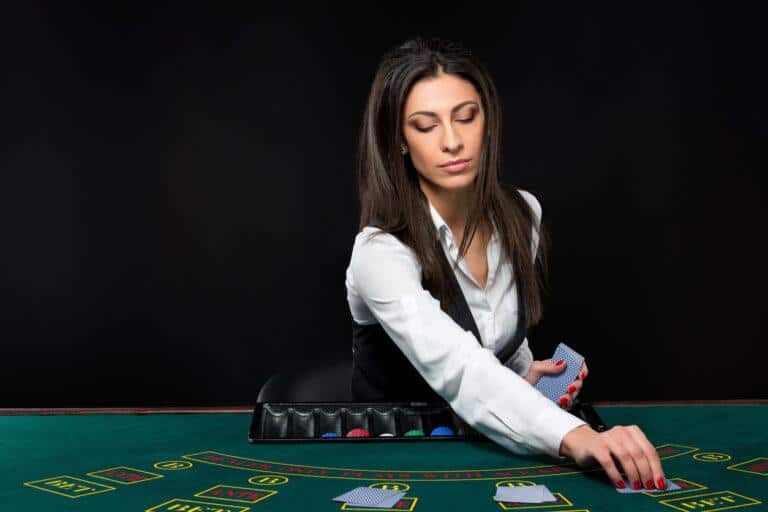 The beautiful girl, dealer, behind a table for game in poker. the dealer deals the cards.